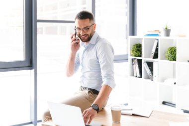 Görüntü modern insanın formal giyim siyah Smartphone'da ofiste tabloda otururken iş bahsediyoruz
