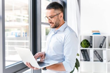 İş merkezinde çalışmalar sırasında gümüş dizüstü tutarak başarı ifade beyaz gömlek giymiş çekici office adam