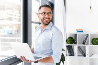 Office çalışan adamın beyaz gömlek bir yana iş merkezi çalışması sırasında gümüş dizüstü tutarken seyir giydiğini görüntüsünü