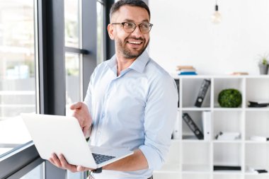 Office çalışan adamın beyaz gömlek bir yana iş merkezi çalışması sırasında gümüş dizüstü bilgisayar kullanırken seyir giydiğini görüntüsünü