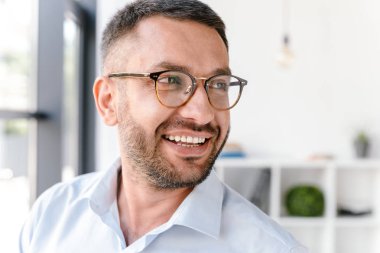 Portre portre yakışıklı adam 30'lu giyen beyaz gömlek ve gözlük bir kenara büyük iş merkezi veya ofis Oda penceresinde yakın dururken arıyorsunuz
