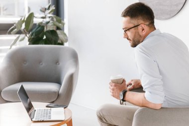 Koltukta oturan ve dizüstü bilgisayar ekranında iş iç bakarken paket servisi olan restoran kahve içme Beyaz tişörtlü yetişkin office adam 30'lu görüntüsünü