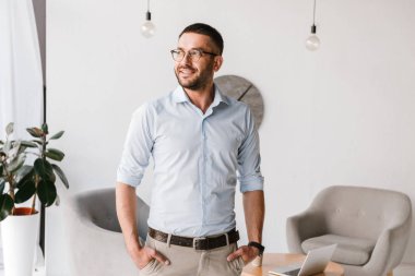 Ofis iç beyazlı duran ve bir kenara mutlu gülümseme ile seyir giyen ciddi adam portresi