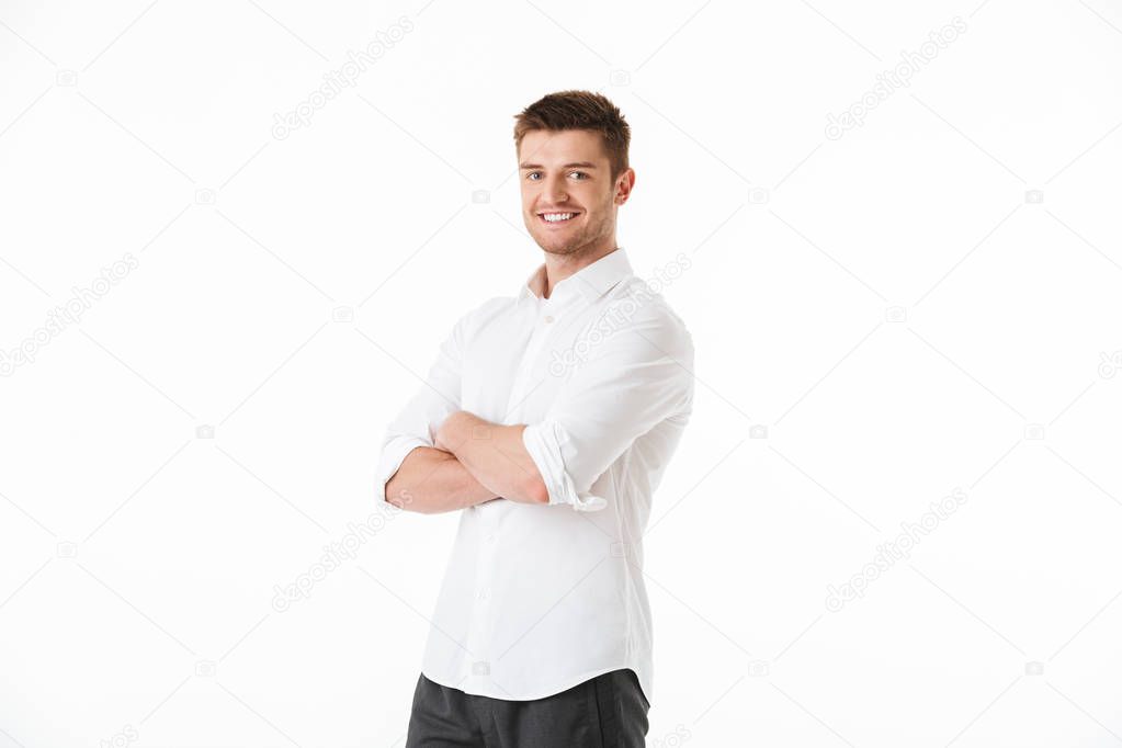 Portrait of a smiling young man standing with arms folded isolated over white background