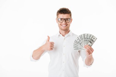 Para banknot tutarak ve başparmak kadar beyaz arka plan üzerinde izole gösteren gözlük kendine güvenen genç bir adam portresi