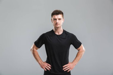 Kollarda gri arka plan üzerinde izole kalça ile ayakta odaklı bir genç sporcu portresi