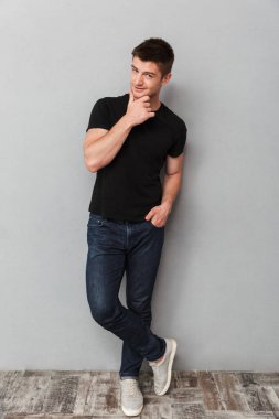 Çekici bir genç adam kameraya gri arka plan üzerinde arıyorsunuz tam uzunlukta portresi