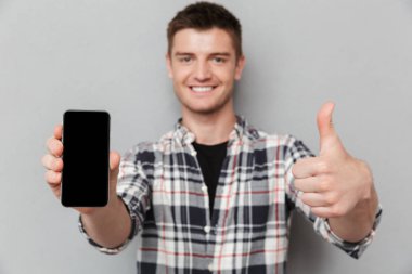 Boş ekran cep telefonu gri arka plan üzerinde gösterilen genç gülümseyen bir adam portresi