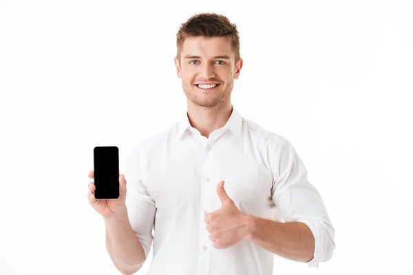 Retrato Joven Sonriente Sosteniendo Teléfono Móvil Blanco Mostrando Los Pulgares —  Fotos de Stock