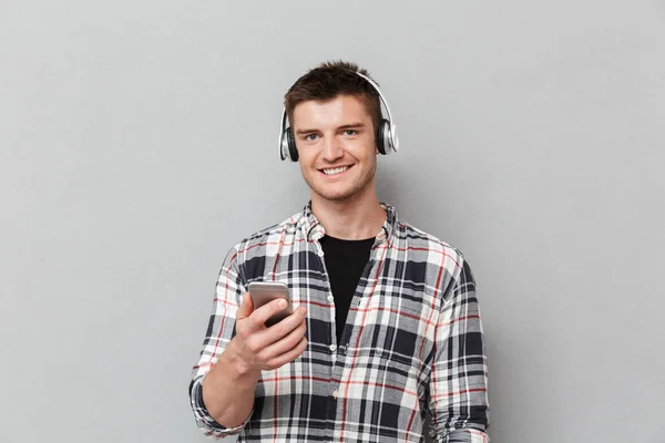 Portrait Smiling Young Man Listening Music Headphones Holding Mobile Phone — Stock Photo, Image