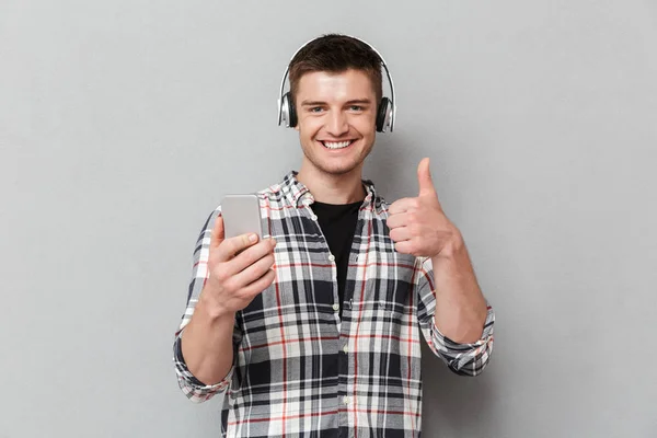 Portrait Satisfied Young Man Listening Music Headphones Holding Mobile Phone — Stock Photo, Image