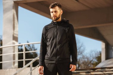 Kulaklıklar açık havada duran bir kendine güvenen genç sporcu portresi