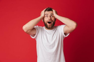 Heyecanlı genç yakışıklı adam kırmızı duvar arka plan üzerinde izole ayakta resmi. Bir kenara arıyorsunuz.