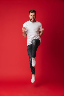 Kazanan jest gösterilen Kırmızı duvar arka plan üzerinde izole fotoğraf yakışıklı genç adamın atlama.