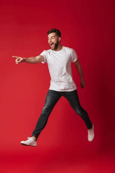 Foto Joven Guapo Saltando Aislado Sobre Fondo Pared Roja Señalando — Foto de Stock