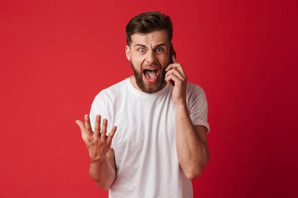 Изображение Кричащего Молодого Человека Стоящего Фоне Красной Стены Разговаривающего Мобильному — стоковое фото
