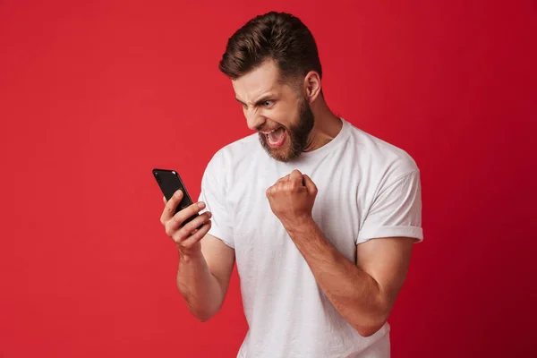 若い男が立って携帯電話を使用して赤い壁背景分離を叫んでのイメージ作る勝者ジェスチャー — ストック写真