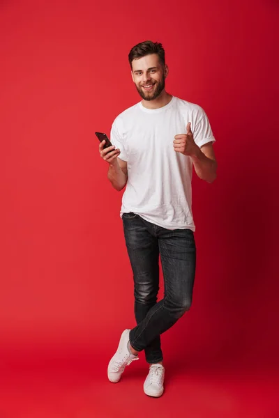 Imagen Joven Feliz Parado Aislado Sobre Fondo Pared Roja Usando — Foto de Stock