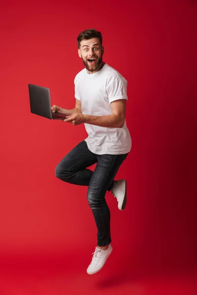 Imagen Joven Sorprendido Saltando Aislado Sobre Fondo Pared Roja Usando — Foto de Stock