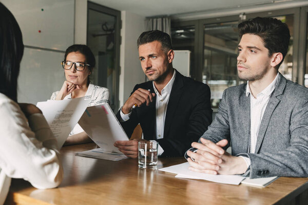 Бизнес, карьера и цемент - комитет деловых людей, сидящих за столом в офисе и опрашивающих женщину во время встречи
