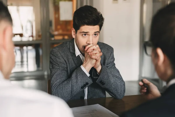 Business, career and placement concept - caucasian uptight male applicant worrying and putting fists together during job interview in office with board of directors