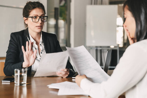 Образ нервной неуверенной азиатки, говорящей и ведущей переговоры с бизнесвумен, сидящей за столом в офисе во время собеседования - бизнес, карьера и концепция найма
