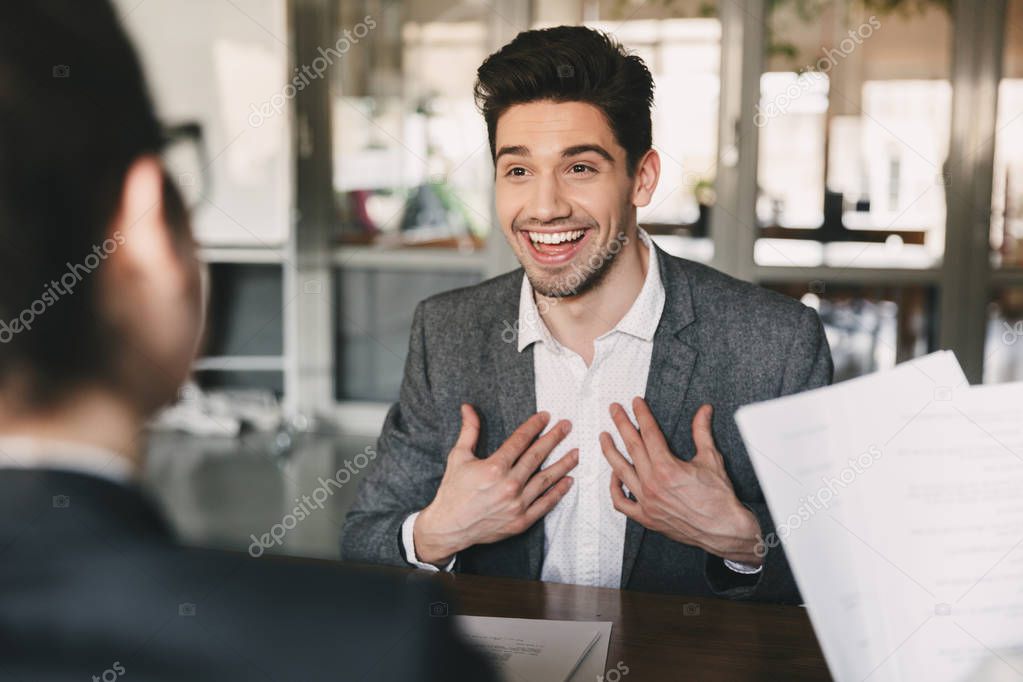 Business, career and placement concept - surprised caucasian man 30s rejoicing and showing at himself when hiring during job interview with employees in office