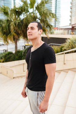 Yakışıklı genç sporcu bir kenara açık havada kulaklık arıyorum portresi.