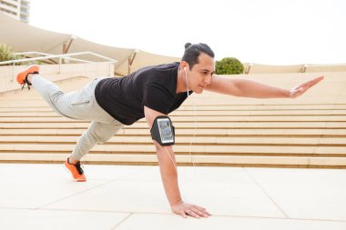 Egzersizler yapmak imge-in güçlü yakışıklı genç sporcu açık havada kulaklık.