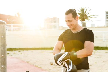 Açık havada bir kenara seyir eldiven giymiş güçlü yakışıklı genç sporcu boxer fotoğrafı.