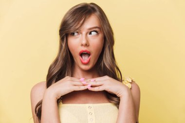 Sarı arka plan bir kenara inceliyorlar izole duran şok genç güzel kadın görüntüsünü.