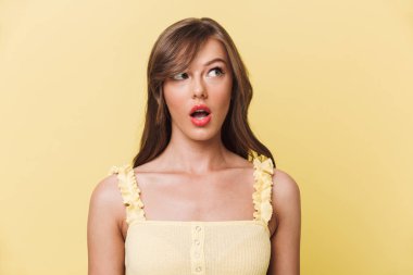 Sarı arka plan bir kenara inceliyorlar izole duran şok genç güzel kadın görüntüsünü.