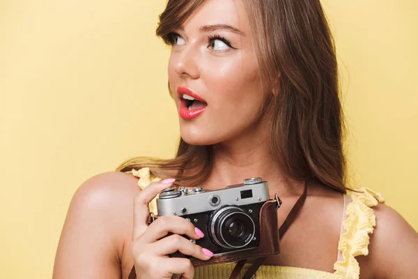 クローズ アップ写真のカメラを保持している 黄色の背景の上分離コピー スペースを見て幸せな若い女の子の肖像画 — ストック写真