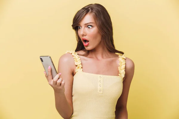 Portrait Shocked Young Girl Looking Mobile Phone Isolated Yellow Background — Stock Photo, Image