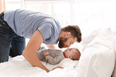 Yakışıklı genç baba baba kapalı evde küçük bir çocuk oğlu ile eğleniyor görüntüsünü.