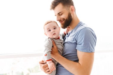 Mutlu genç adam baba baba diğer görüntüsünü elinde tutan küçük bir çocuk oğlu evde kapalı.