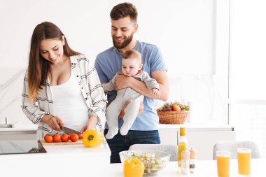 Mutlu genç çift anne mutfakta yemek küçük çocuk bebek oğulları ile sevgi dolu görüntüsünü.