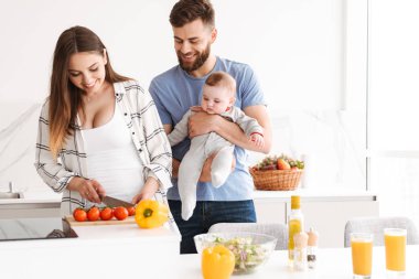 İnanılmaz genç çift anne mutfakta yemek küçük bebek oğulları ile sevgi dolu fotoğraf.