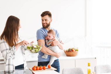 Mutlu genç çift anne mutfakta yemek küçük çocuk bebek oğulları ile sevgi dolu görüntüsünü.