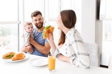Mutlu sevgi dolu çift anne mutfakta yemek küçük bebek oğulları ile fotoğraf var bir kahvaltı.