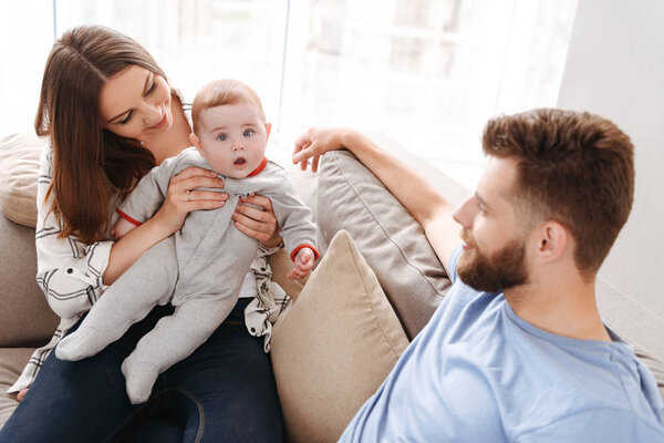 Image of happy young family. Parents having fun with their little child indoors at home.