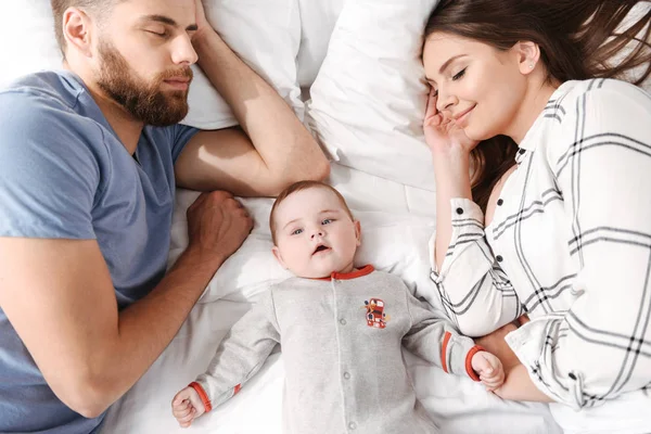 Sevimli genç aile fotoğrafı. Yatakta kapalı evde uyuyor, küçük çocukları ile anne yalan.