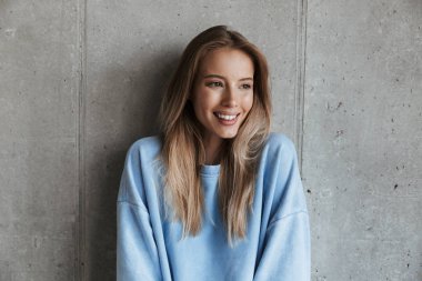 Genç neşeli mutlu güzel kadın bir kenara arka plan gri duvar seyir duran resim.