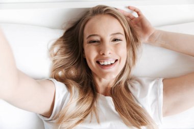 Sevimli güzel komik genç kadın kapalı evde fotoğraf kamera yalan yatakta tarafından selfie olun.