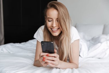 Fotoğraf genç güzel güzel kadın yalan yatakta kapalı evde cep telefonunuzun.
