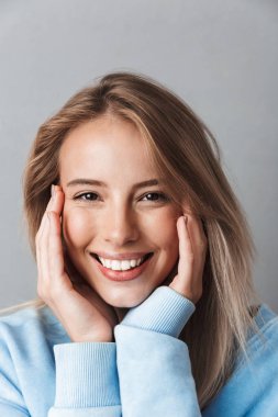 Mavi kazağı gri arka plan üzerinde izole kamera bakarak mutlu bir genç kızın yakın çekim