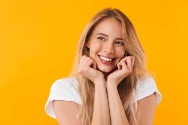 Sevimli smilig genç sarışın kız uzakta sarı arka plan üzerinde izole bir portresi