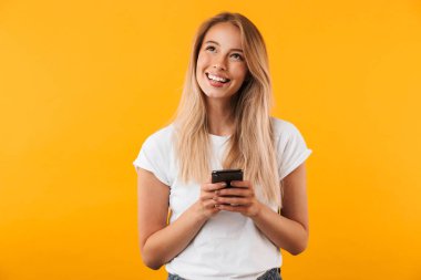 Hareket eden telefon tutarak ve sarı arka plan üzerinde izole ararken bir gülümseyen genç sarışın kız portresi