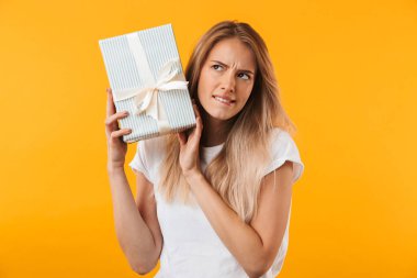 Mevcut kutusu izole sarı arka plan üzerinde tutan bir karışık sarışın genç kadın portresi