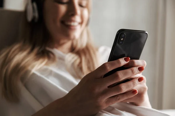 Evde Bir Kanepede Döşenmesi Sırasında Cep Telefonuyla Kulaklıklar Içinde Neşeli — Stok fotoğraf